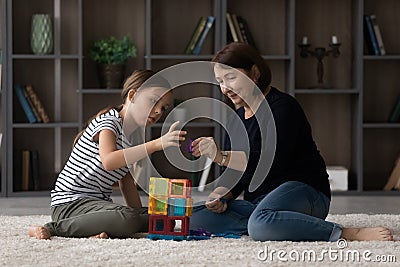 Caring older grandma help granddaughter build from colorful magnetic constructor Stock Photo
