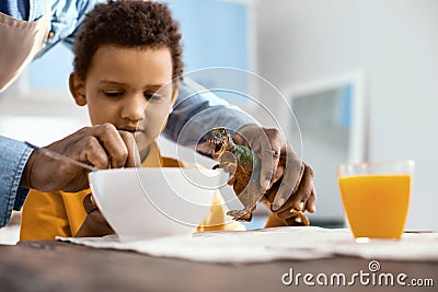 Caring parent helping his little son feed toy dinosaur Stock Photo