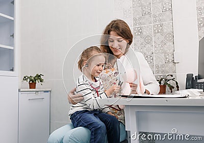 a caring pediatrician plays with a small patient soothing her during the examination. Stock Photo