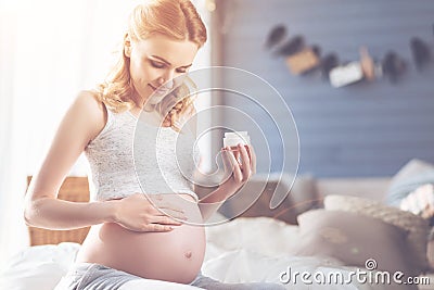 Caring pregnant woman applying body cream Stock Photo