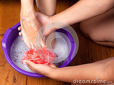 Caring for a pregnant woman the husband washes his wife`s feet in soapy water Stock Photo