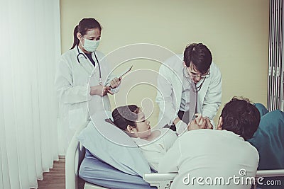 Team of pediatricians examines the health of a pregnant woman, with her husband expecting side by side in the hospital room. Stock Photo