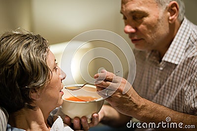 Caring senior man feeding his sick wife Stock Photo