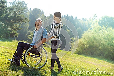 Caring wife carrying her disabled husband in a wheelchair Stock Photo