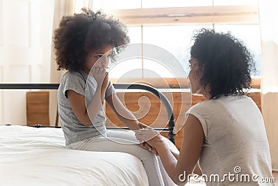 Worried african mother holding hand comforting sad little daughter Stock Photo