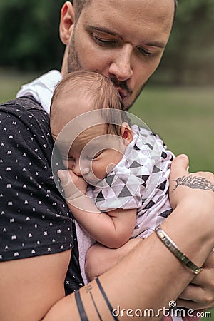 Caring young father cradling his adorable baby boy outside Stock Photo