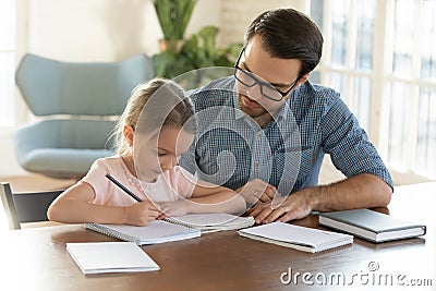 Caring young father helping little daughter with homework. Stock Photo