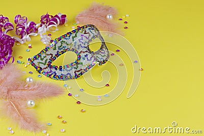 Carnival. Festive background. Venetian. Carnival mask with feathers on a yellow background with tinsel. Brazilian. Copy space Stock Photo