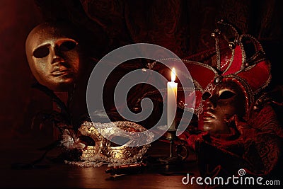 Carnival masks and small brass candlestick with burning candle Stock Photo