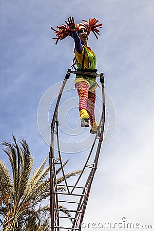 Carnival of Nice, Flowers` battle. An acrobat woman with clown costume on sky background Editorial Stock Photo