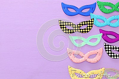 carnival party celebration concept with collection of colorful masks over purple wooden background. Top view. Flat lay. Stock Photo