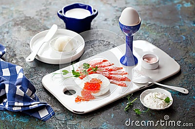 Carnivore diet breakfast, smoked salmon, egg, sheep cheese with red caviar, cottage cheese, goats butter, cream fresh on a ceramic Stock Photo