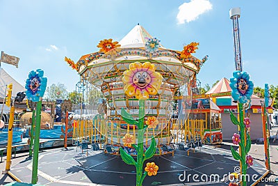 Carousel chains for children in bright colors during a fair in an Italian park flower shaped lights Editorial Stock Photo