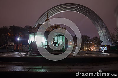 Carousel in the fog in historical place People`s Friendship Arch in city Kiev. Editorial Stock Photo