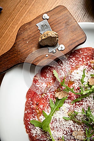 Carpaccio with parmesan, truffles and arugula on a white plate Stock Photo