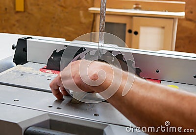 Carpenter adjusting the blade using a right angle square at the table saw Stock Photo