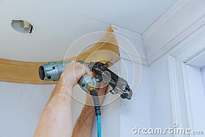 Carpenter brad using nail gun to Crown Moulding framing trim, with the warning label that all power tools Stock Photo