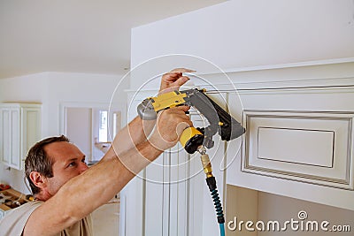 Carpenter brad using nail gun to Crown Moulding on kitchen cabinets framing trim, Stock Photo