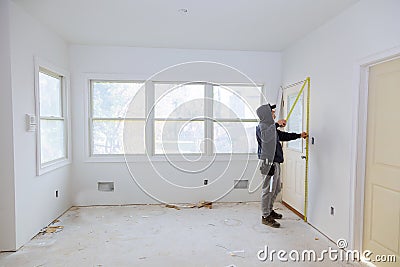 Carpenter brad using nail gun to moldings on doors, framing trim, Editorial Stock Photo