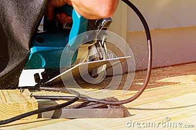 Carpenter building cutting electric circular saw wooden deck. Stock Photo