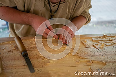 Carpenter carving wood with chisel at medival festival - close up Stock Photo