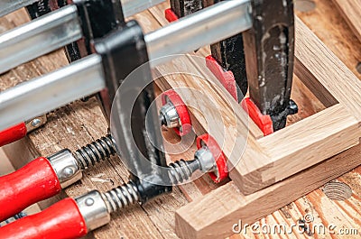 Carpenter clamps are fixed to boards. Gluing joinery in workshop Stock Photo