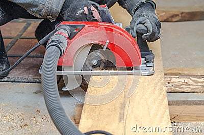 Carpenter cuts wooden board with hand-held circular saw Stock Photo