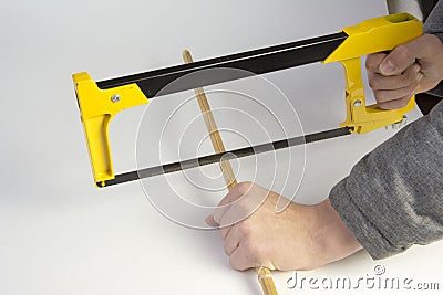 A carpenter cuts a wooden stick with a hand saw on a white background Stock Photo