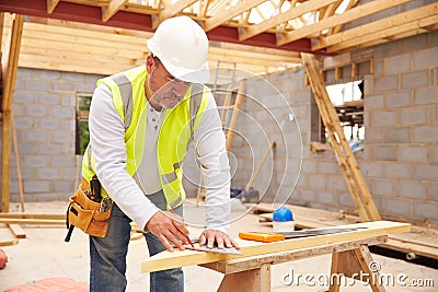 Carpenter Cutting House Roof Supports On Building Site Stock Photo