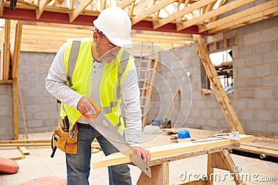 Carpenter Cutting House Roof Supports On Building Site Stock Photo