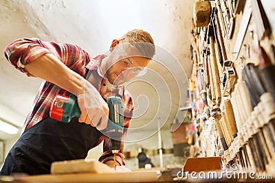 Carpenter with drill drilling plank at workshop Stock Photo