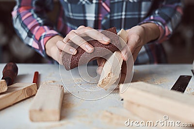 Carpenter hands polishing wooden planks with a sandpaper. Concept of DIY woodwork and furniture making Stock Photo
