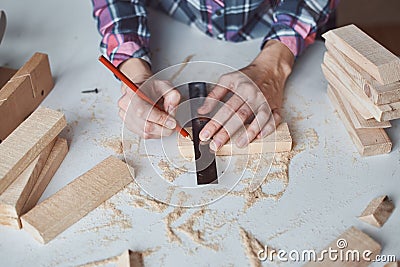 Carpenter hands taking measurement with a pencil of wooden plank. Concept of DIY woodwork and furniture making Stock Photo