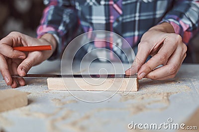 Carpenter hands taking measurement with a pencil of wooden plank. Concept of DIY woodwork and furniture making Stock Photo