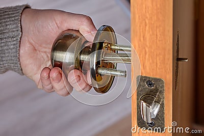 Handyman pushes the door knob spindle through the face bore and the latch assembly Stock Photo