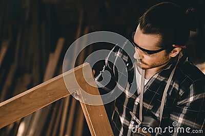 Carpenter man professional skilled in wood work looking detail of masterpiece woodcraft in furniture workshop Stock Photo