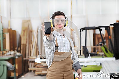 Carpenter man show the mobile phone isolated in carpentry background Stock Photo
