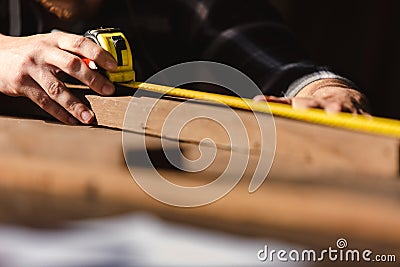 Carpenter man using measuring tape looking wood size at workspace. craftsman profession in wood factory Stock Photo