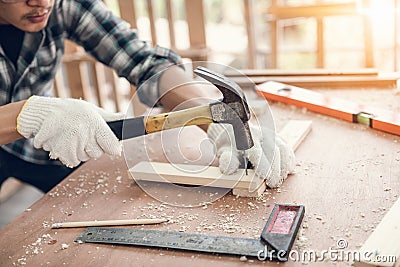 Carpenter Man is Working Timber Woodworking in Carpentry Shop, Craftsman is Hammering a Nail into Timber Frame for Wooden Stock Photo