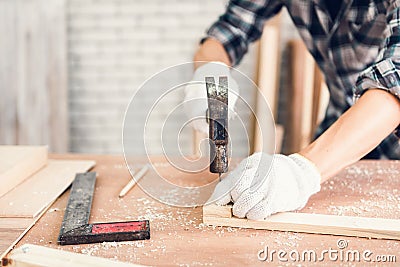 Carpenter Man is Working Timber Woodworking in Carpentry Shop, Craftsman is Hammering a Nail into Timber Frame for Wooden Stock Photo