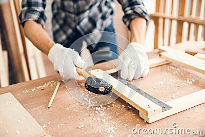 Carpenter Man is Working Timber Woodworking in Carpentry Workshops, Craftsman is Using Rubber Hammer Adjusting Timber Frame for Stock Photo