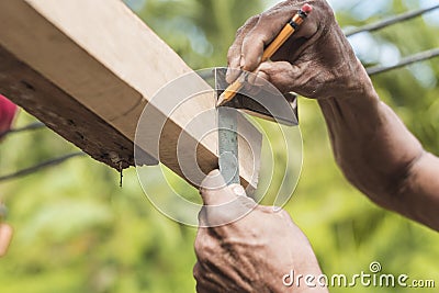 A carpenter marks the excess edge of a wood rafter with a pencil. Using a L-square ruler to make a straight line. Building a Stock Photo