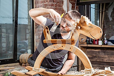 Carpenter paints children`s wooden toy Stock Photo