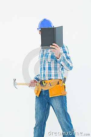 Carpenter reading book while holding hammer Stock Photo