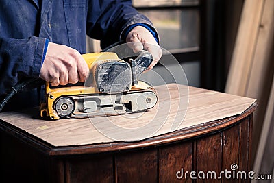 Carpenter restoring furniture with belt sander Stock Photo