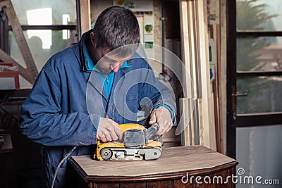 Carpenter restoring furniture with belt sander Stock Photo