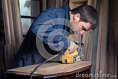 Carpenter restoring furniture with belt sander Stock Photo