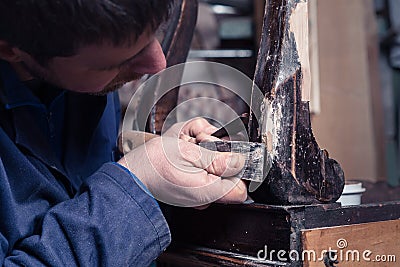 Carpenter restoring Wooden Furniture with plaster and putty Knife Stock Photo