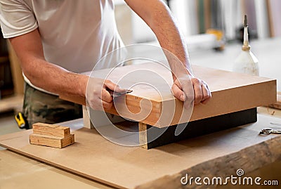 Carpenter sanding the edge of a wooden block Stock Photo
