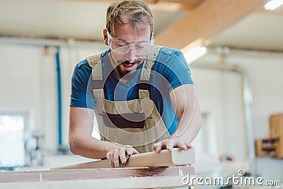 Carpenter sanding piece of wood by hand Stock Photo